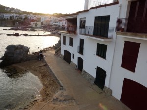 Escena costanera de Calella amb edificis blancs, camí de pedra i mar tranquil