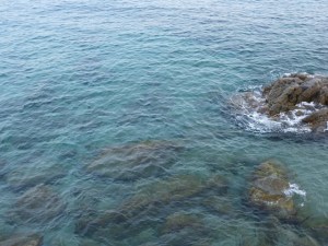 Vista del mar a Calella amb roques submergides i aigües blaves de diferents tonalitats