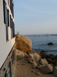 Vista costanera de Calella amb edifici blanc, roques i mar tranquil