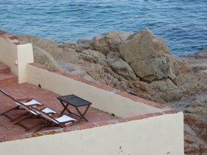 Terrassa amb gandules davant del mar a Calella, amb roques i aigua clara