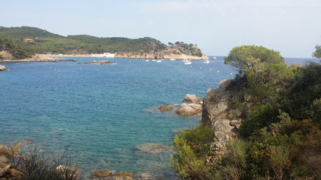 Vista costanera des del camí de ronda entre Cala Fosca i S’Alquer amb roques, vegetació i barques ancorades