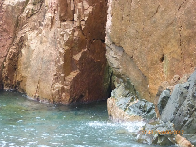 Fotografia de penya-segats costaners amb aigua a la base i textura rocosa prominent