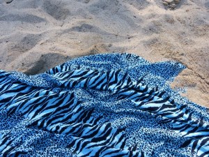 Fotografia d’un teixit amb estampat de zebra blau i negre sobre sorra de platja