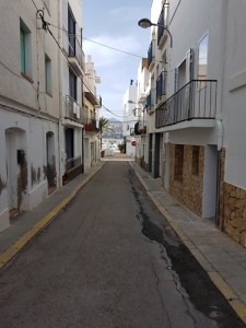 Carrer estret de Llançà amb edificis blancs i cel serè