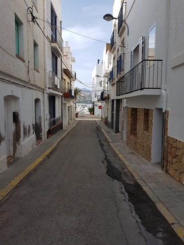Carrer estret de Llançà amb edificis blancs i cel serè