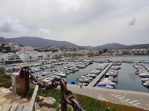 Port de Llançà amb embarcacions, cel gris i fons muntanyós
