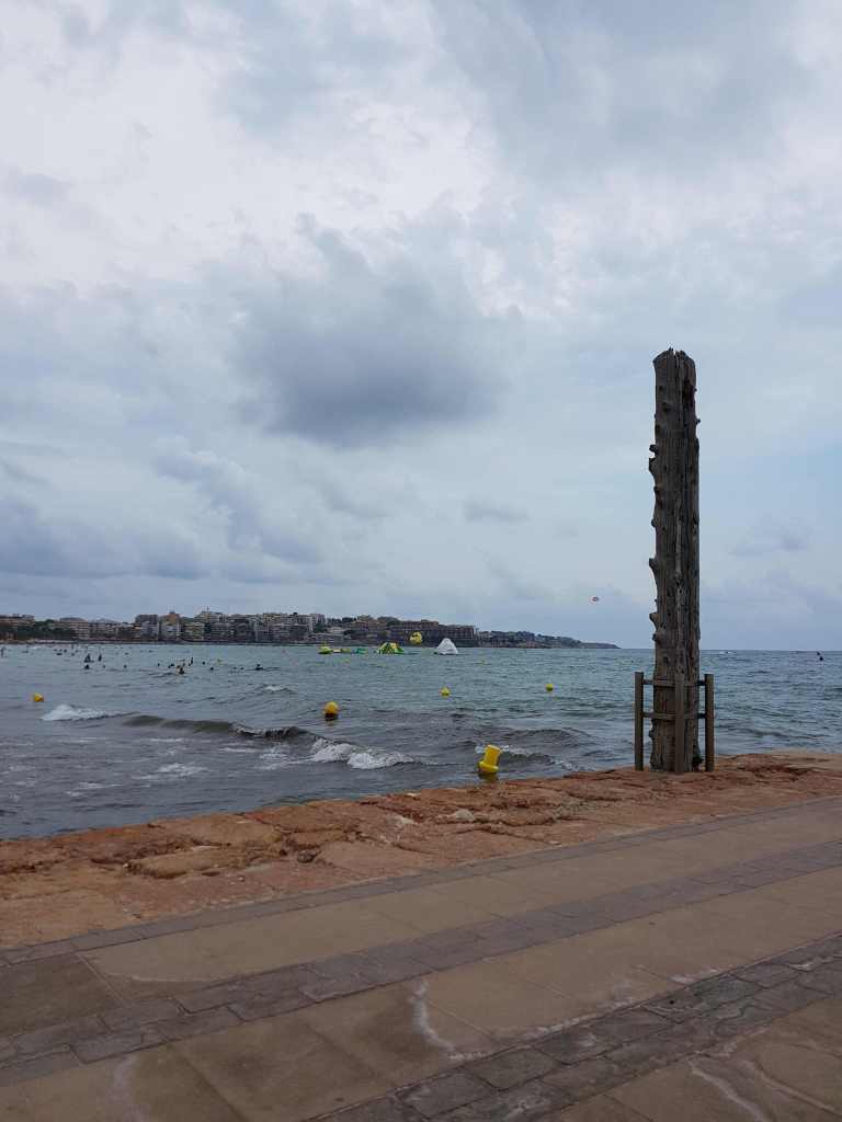 Espigó de Salou amb mar tranquil, boies i cel ennuvolat
