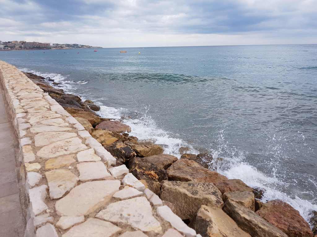 Passeig de pedra al port de Salou amb onades i cel ennuvolat