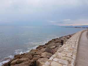 Passeig de pedra al port de Salou amb mar en calma i cel gris