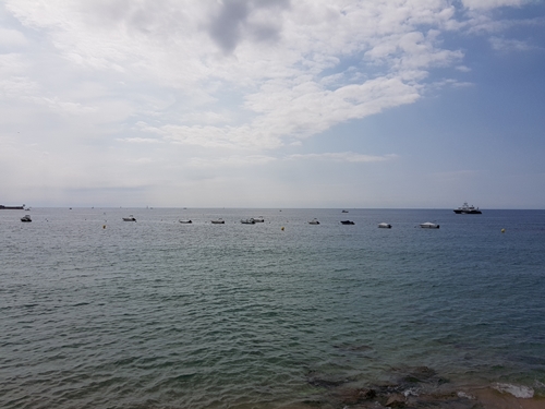 Barques flotant a l’horitzó amb mar en calma i cel parcialment ennuvolat