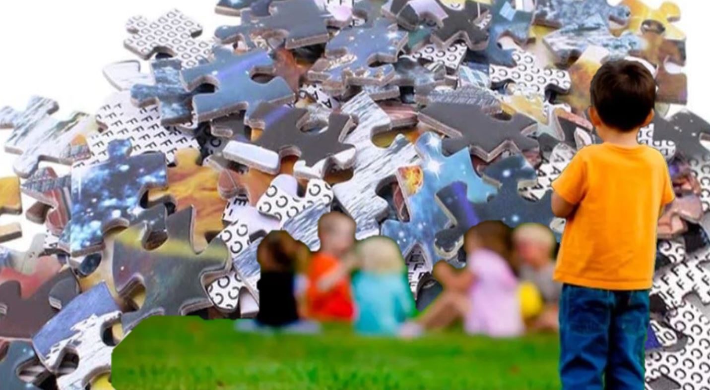 Nen amb samarreta groga davant mural de peces de puzzle amb imatges