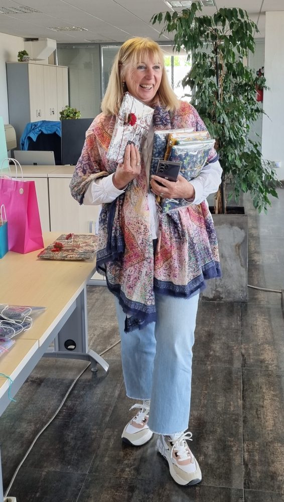 Persona somrient amb objectes artesanals davant d’una planta, fons editat