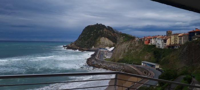 Vista des d’un balcó sobre vila costanera amb mar Cantàbric i cel gris