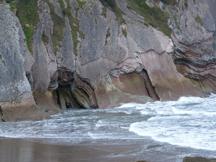 Penya-segat amb estratificacions erosionades i escuma blanca del mar Cantàbric