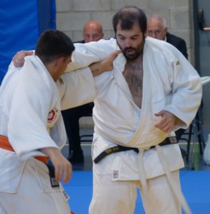 Dos judokes en combat sobre tatami blau amb espectadors al fons
