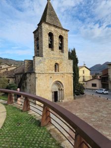 Campanar de pedra de l’església de Llanars amb fons muntanyós