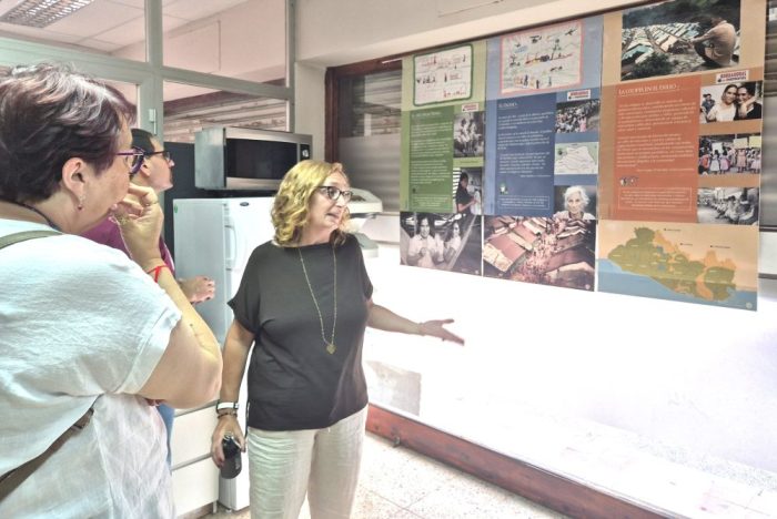 Fotografia de tres persones davant una exposició mural explicativa