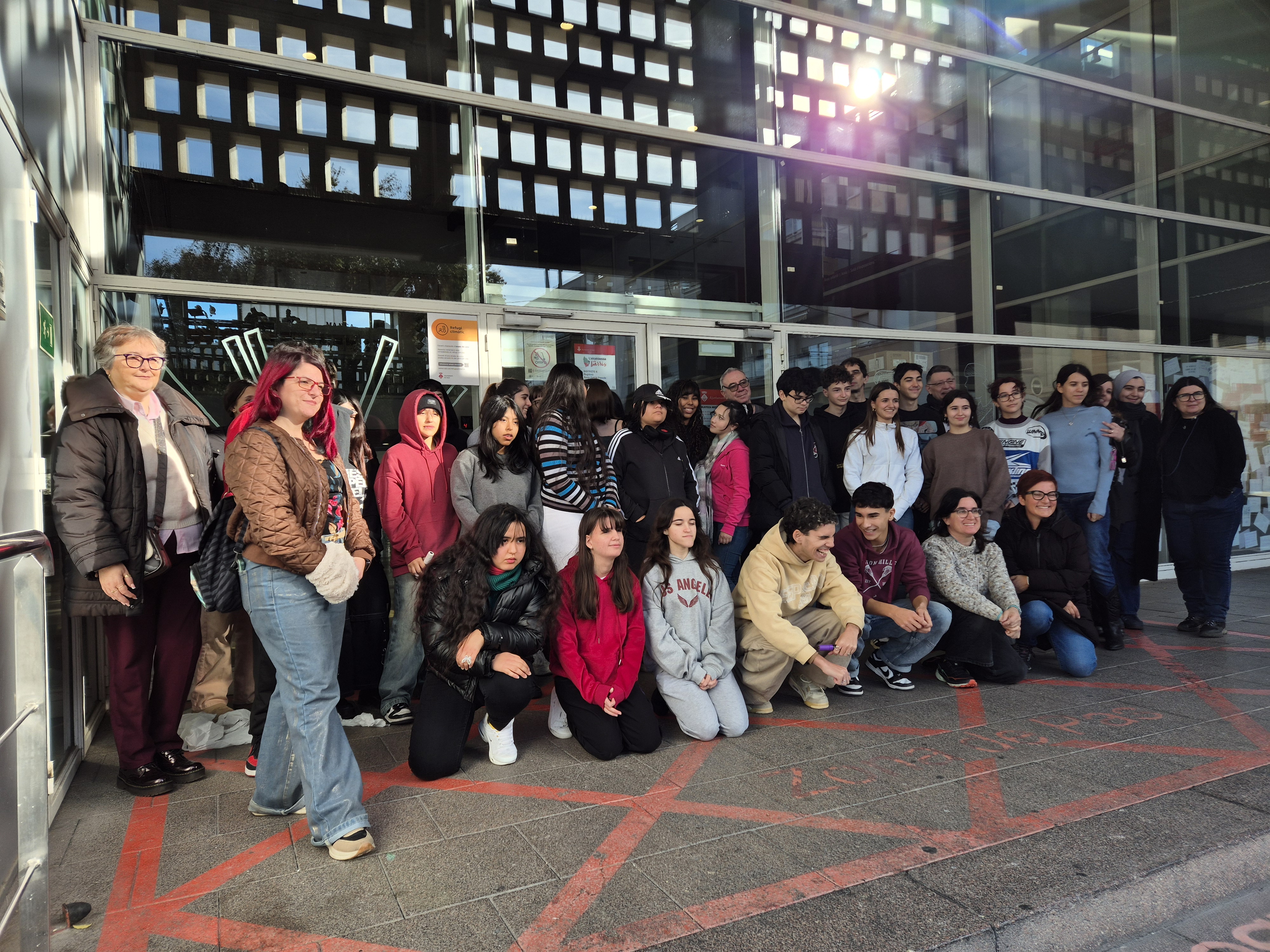 Fotografia col·lectiva davant d’un edifici amb senyalització vermella