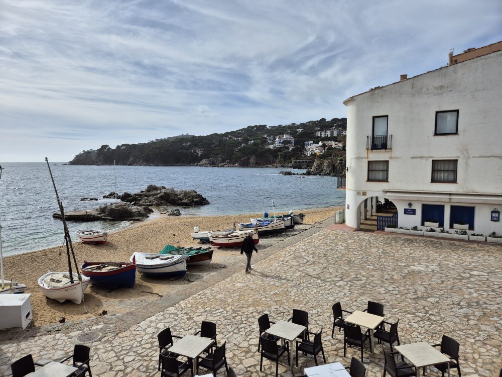 Barques a la platja de Calella de Palafrugell amb arcades blanques i mar mediterrani al fons